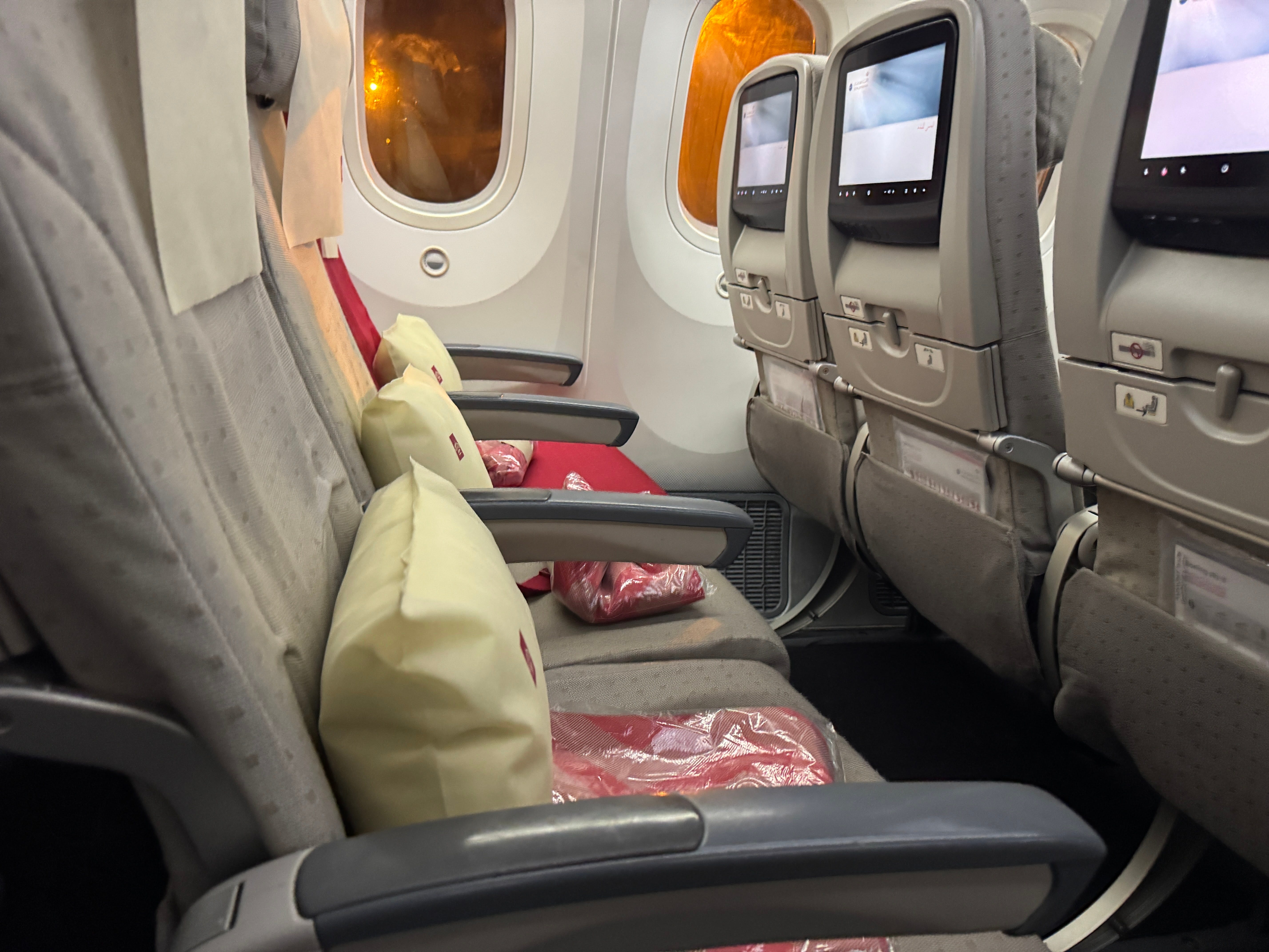 Side view of Row of Air Jordanian plane seats with red blankets, pillows on seats