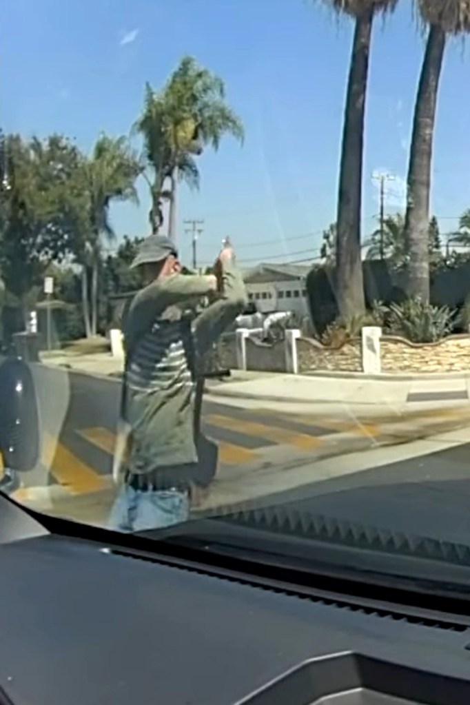 Rudy Anthony Martinez II holding a shovel above his head, seen from a car's windshield.