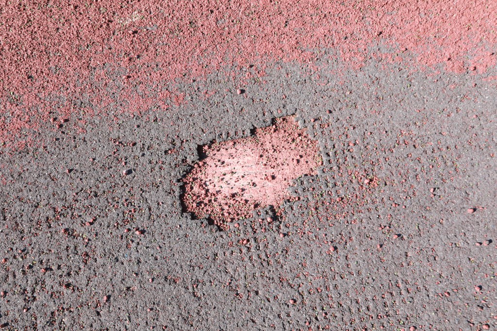 Red and black granulated material on a surface.