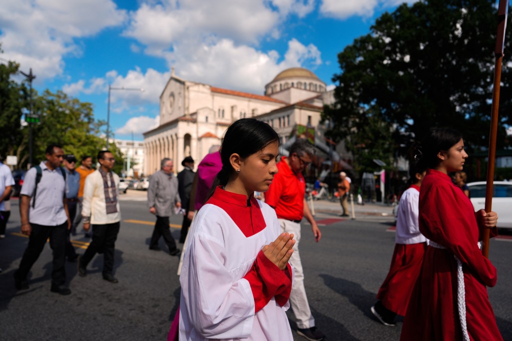 People walk in a procession from Shrine of the Sacred Heart to Cathedral of St. Matthew the Apostle.