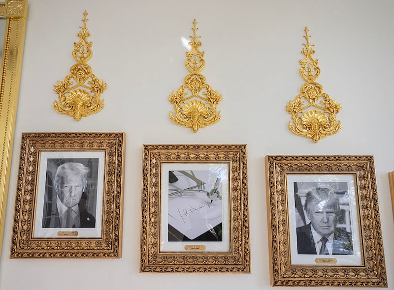 Framed portraits of US President Donald Trump flank a image of former US President Joe Biden's signature and an autopen along 