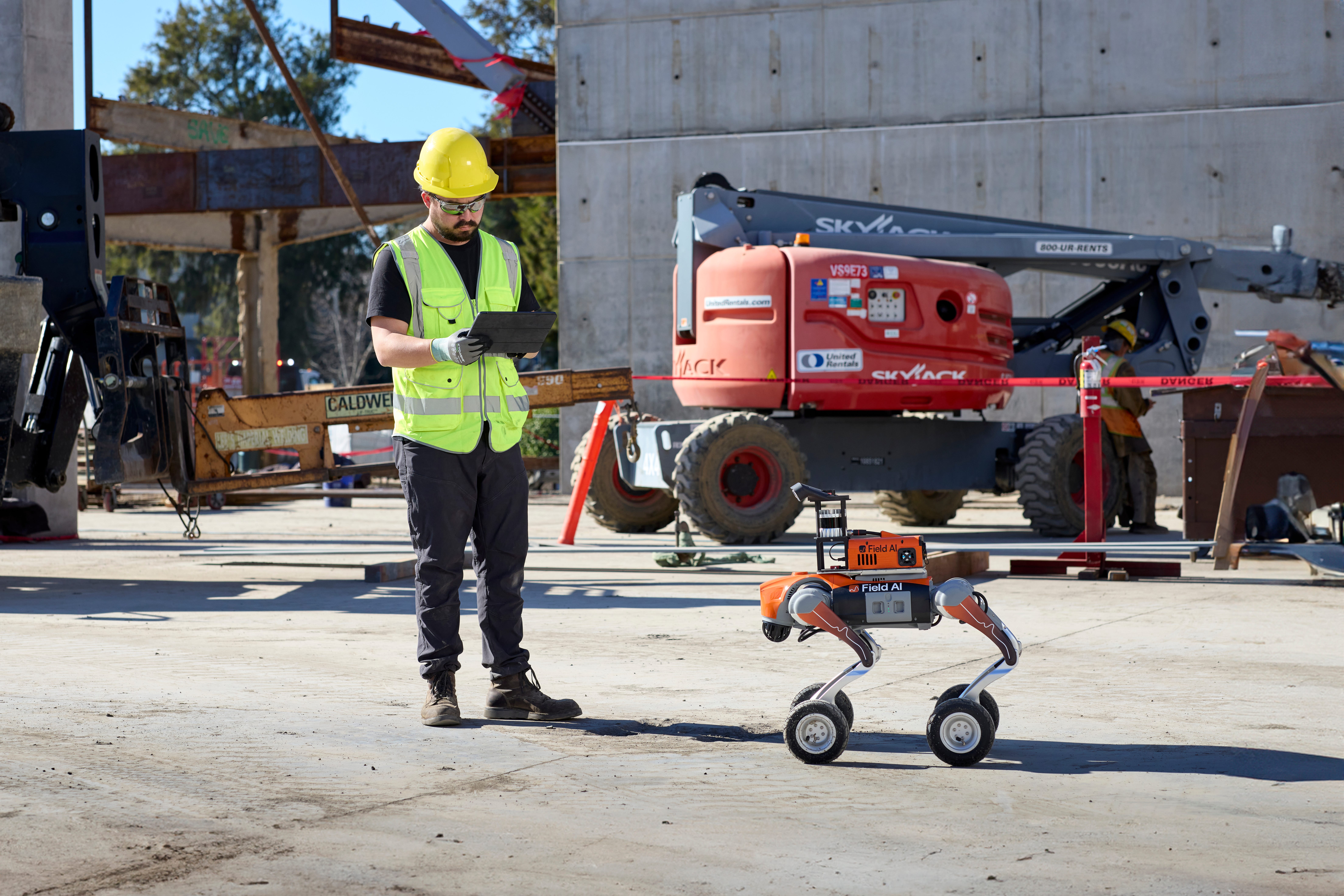 A FieldAI robot operating alongside a construction worker
