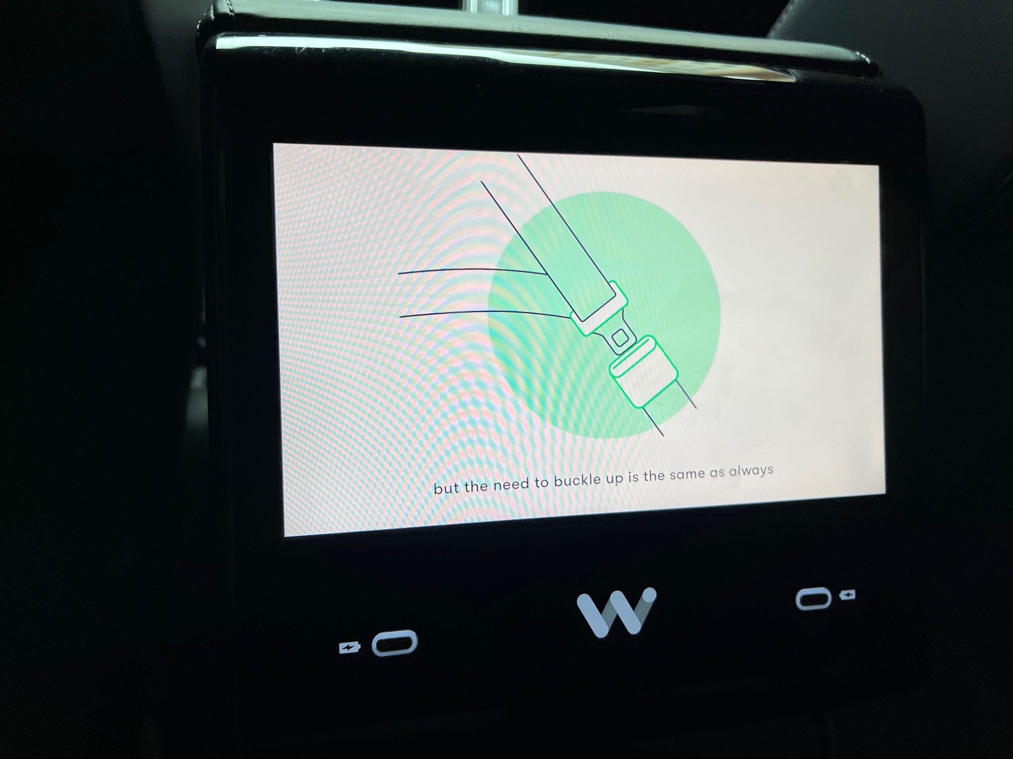A screen in a Waymo car tells passengers in the back seat to buckle their seatbelts.