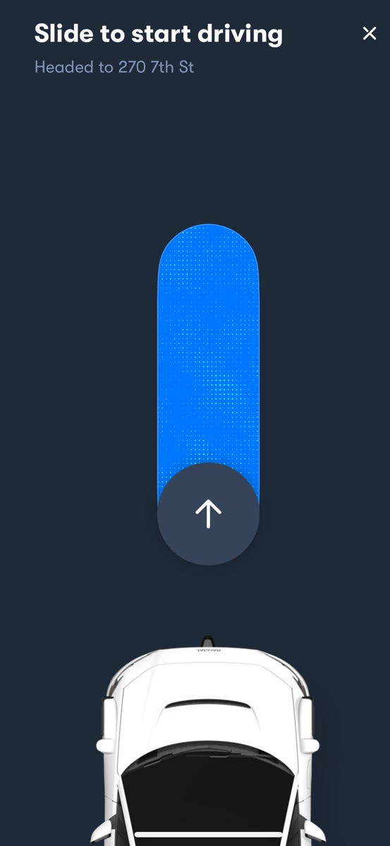 A prompt on a phone screen tells a Waymo rider to slide a button in order to begin their ride.
