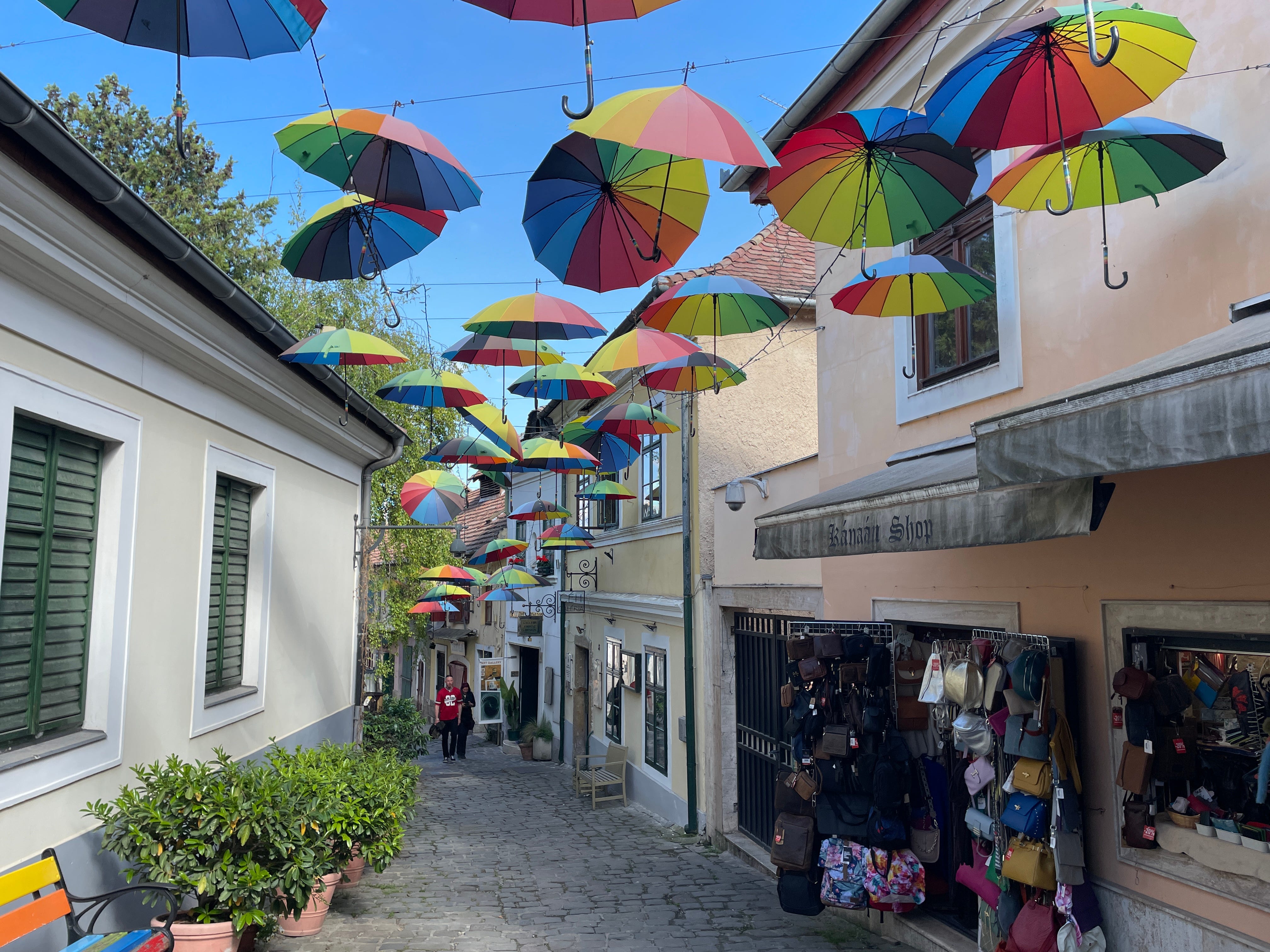 An alley in Szentendre, Hungary, with rainbow umbrellas hanging above the street.
