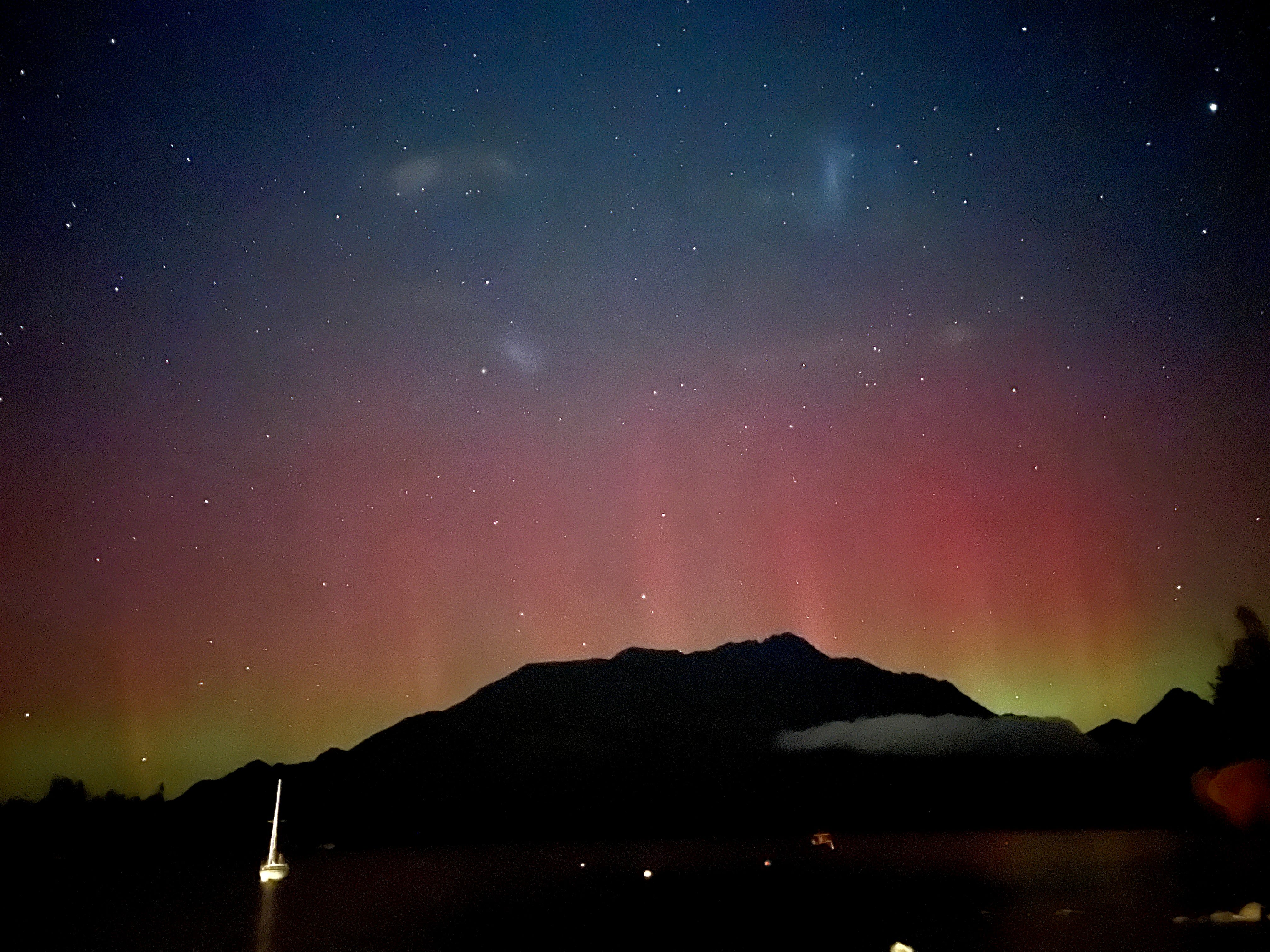 View of colorful auros in sky above dark mountains