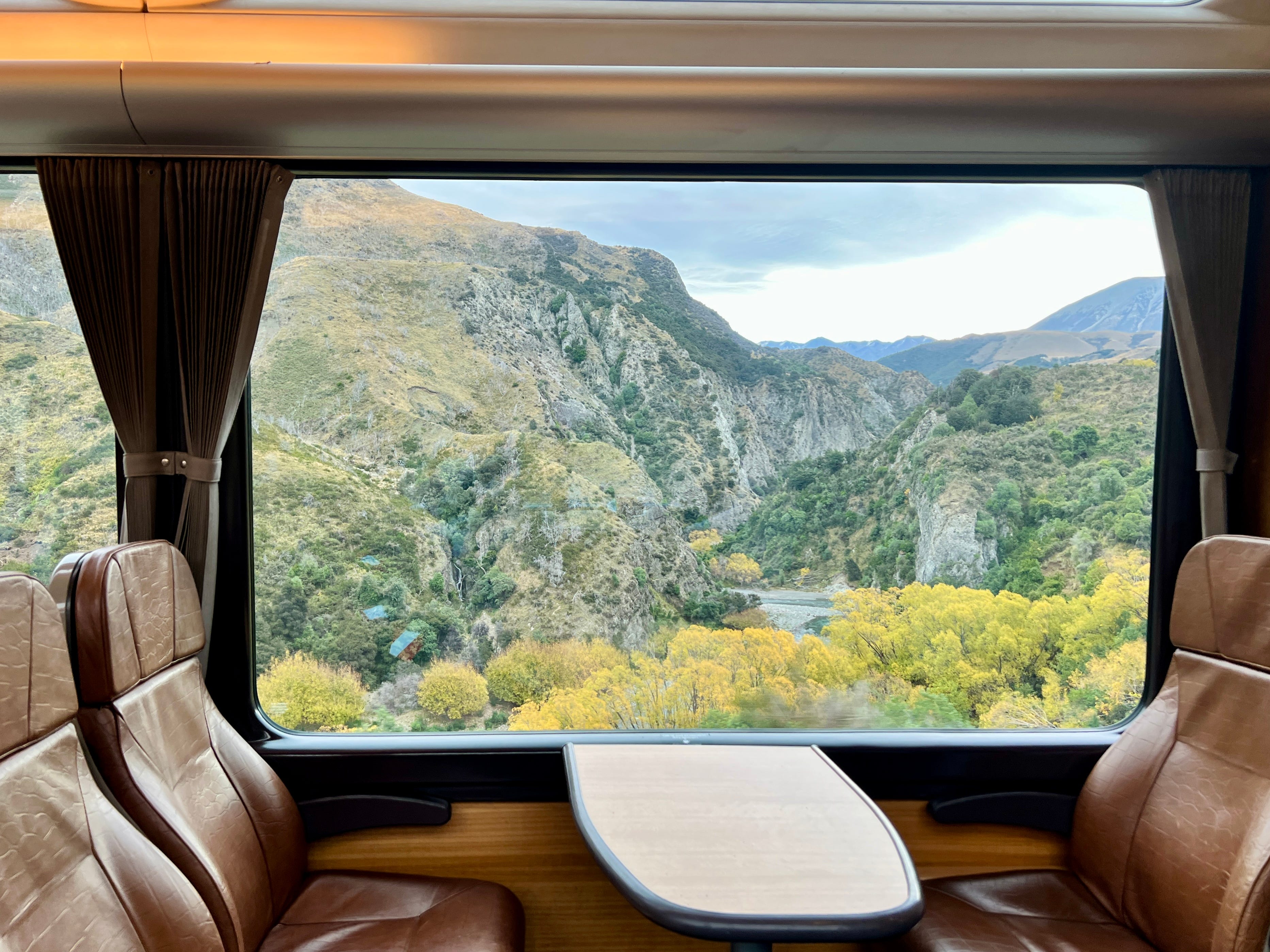 View of mountains, trees outside of TranzAlpine train window