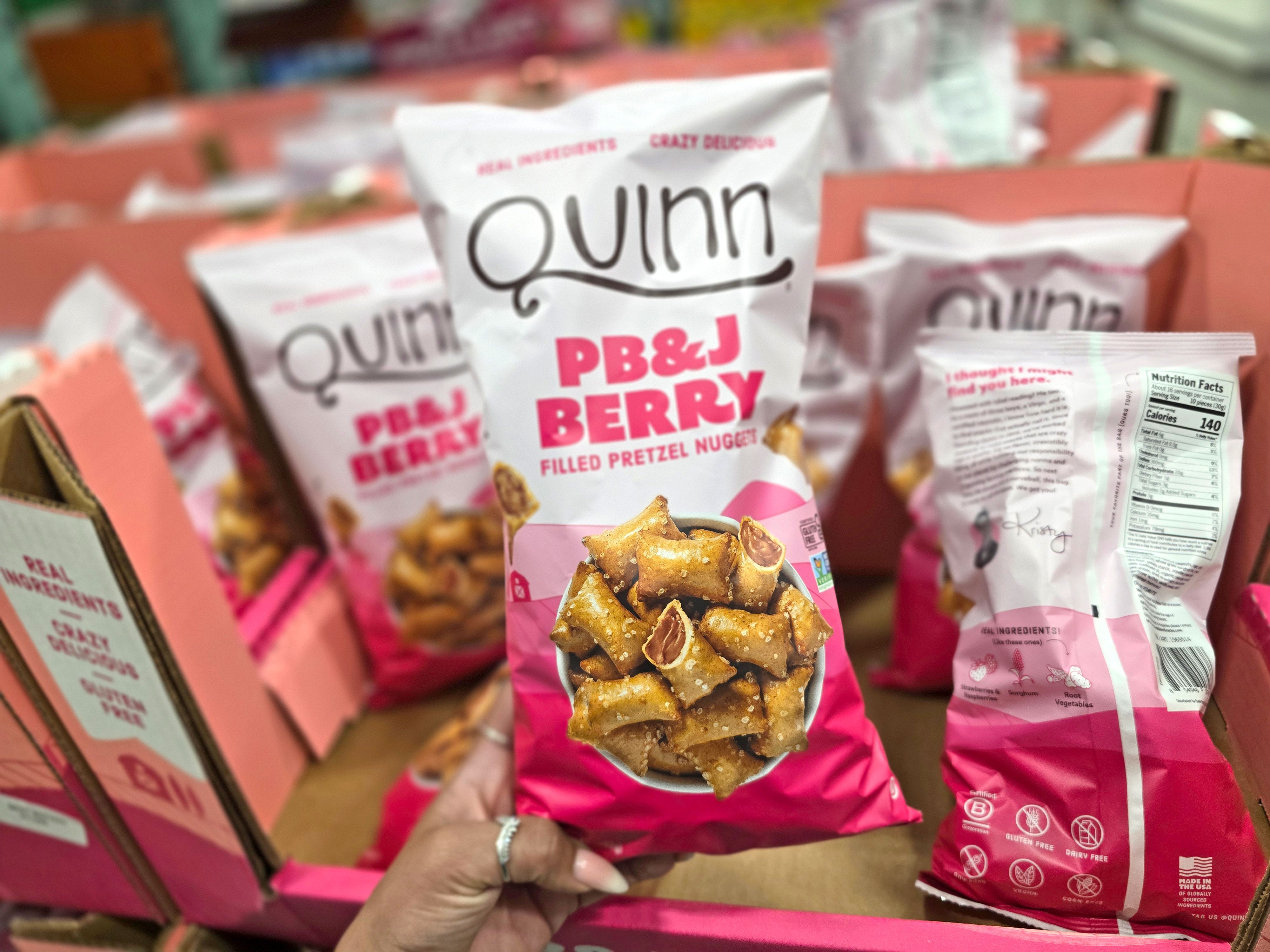 A hand holding a bag of Quinn PB&J berry pretzels.