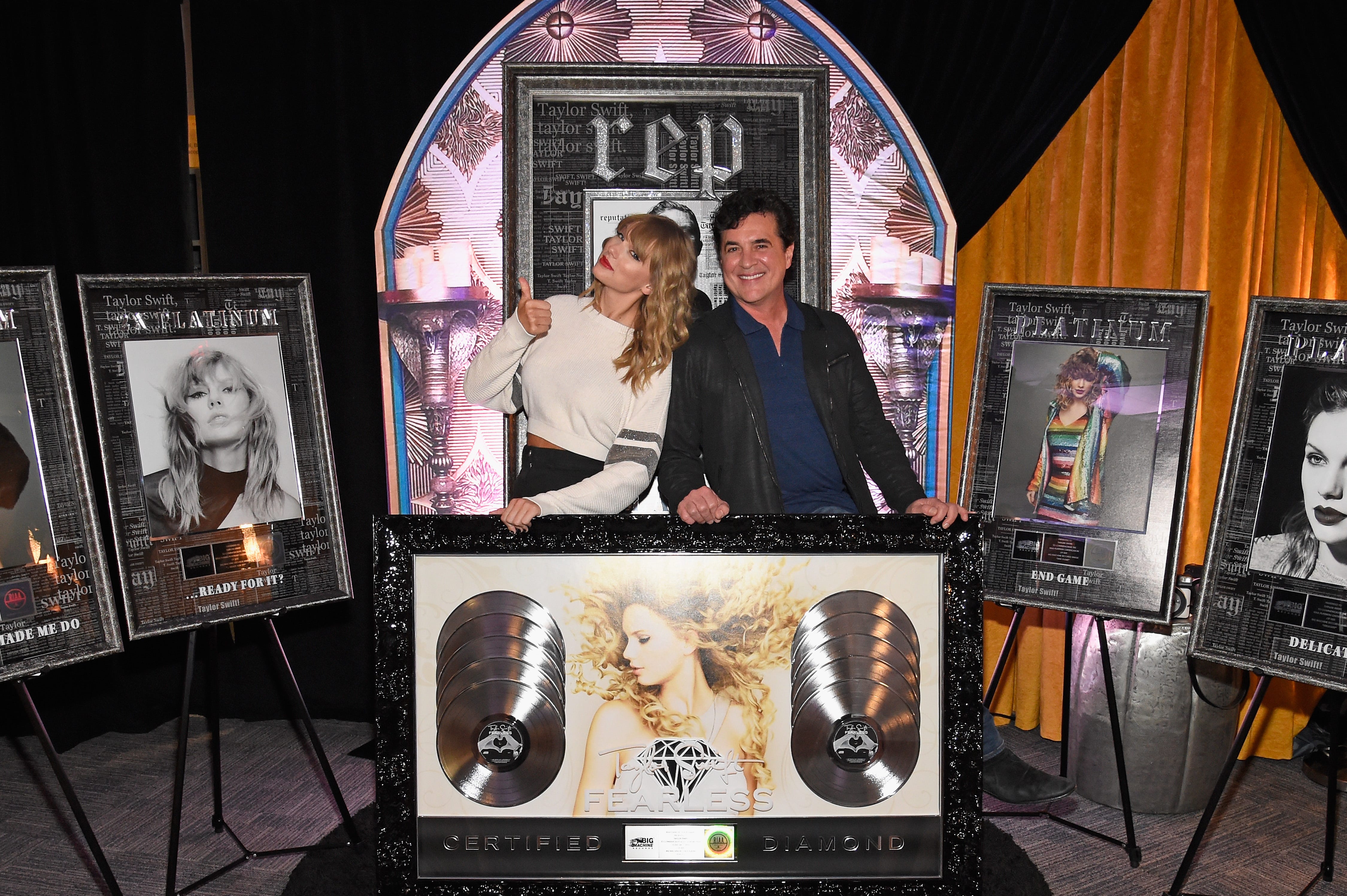 Taylor Swift and Scott Borchetta pose with certification plaques for her albums 