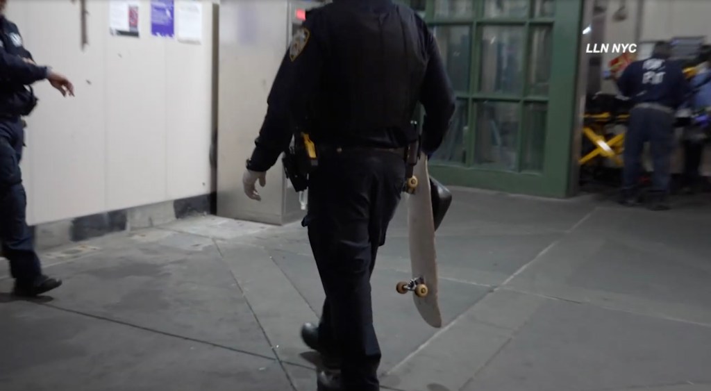 Police officer walking with a skateboard.