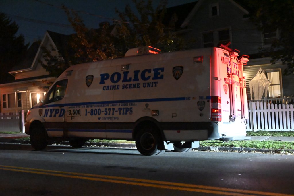 NYPD Crime Scene Unit van parked on a street with a house in the background.