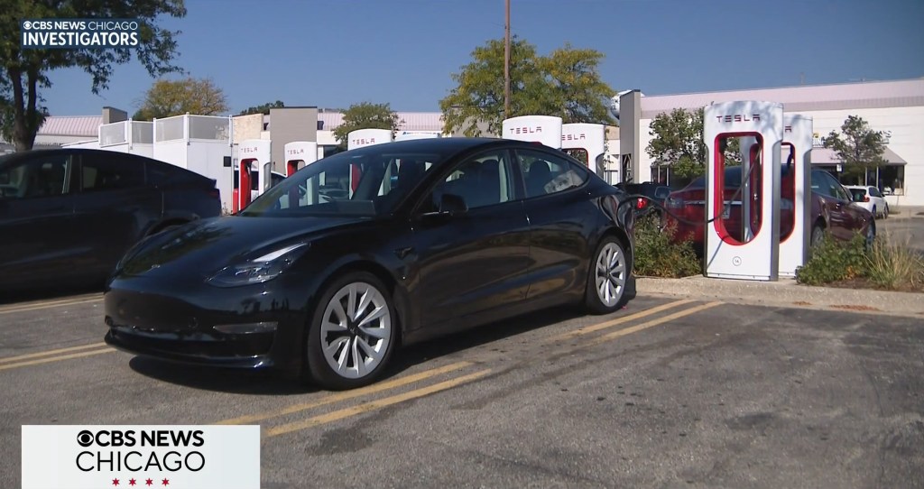 A black Tesla parked in front of Tesla charging stations.