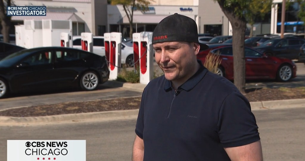 Man in a Chicago Bears hat stands in front of Tesla charging stations.