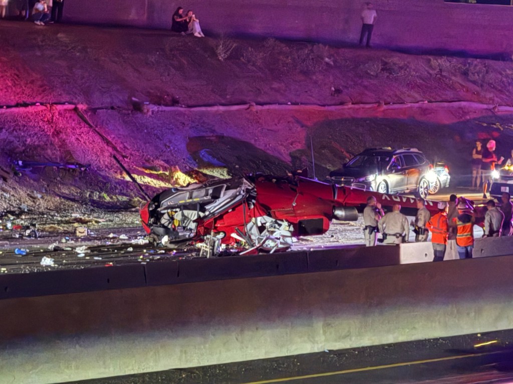 Law enforcement officers stand near the wreckage of a helicopter that crashed on eastbound Highway 50 in Sacramento, Calif., Monday, Oct. 6, 2025. 