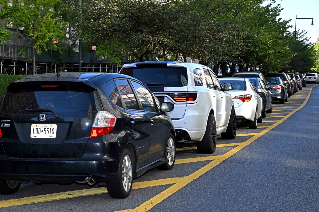 Multiple cars parked on the side of a street with yellow markings.