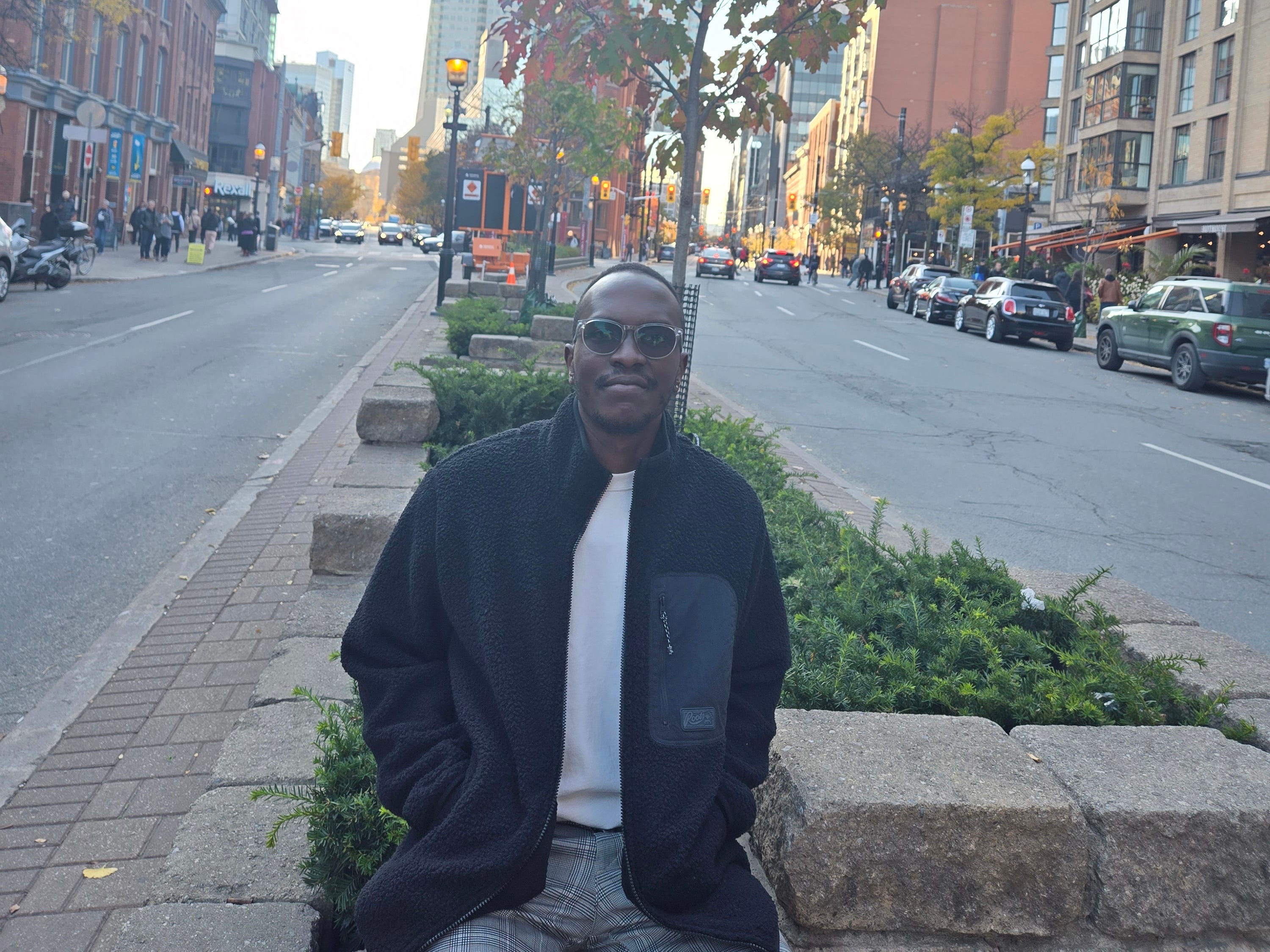 Mwangi Wanjau sitting on a wall in Toronto.