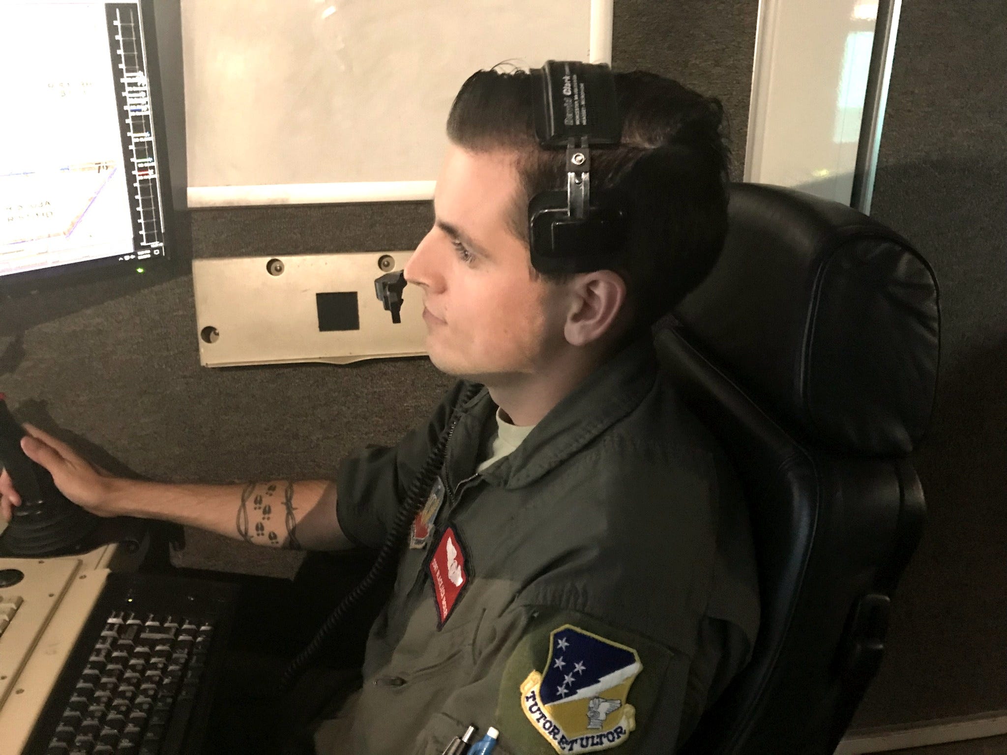 A person in military attire sitting at a desk with a joy stick.