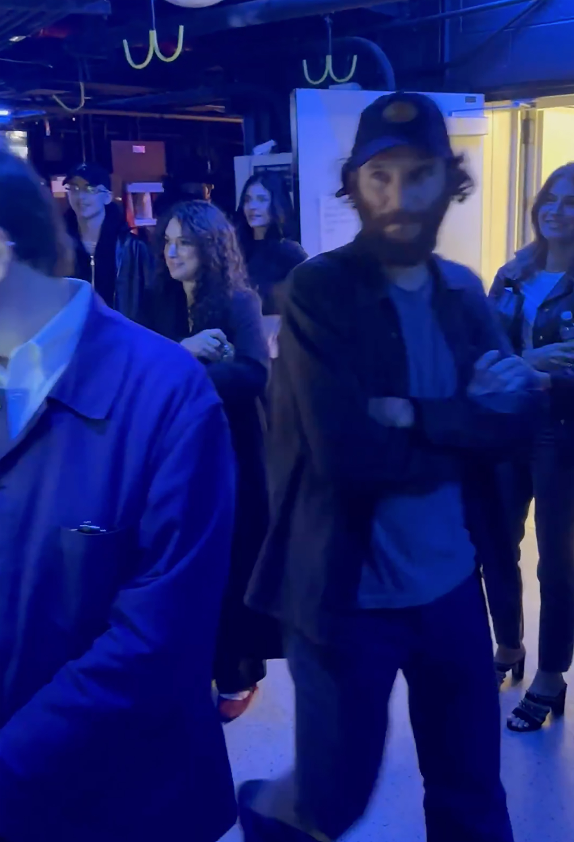 Timothée Chalamet walking backstage, with Kylie Jenner in the background trying to fly under the radar.