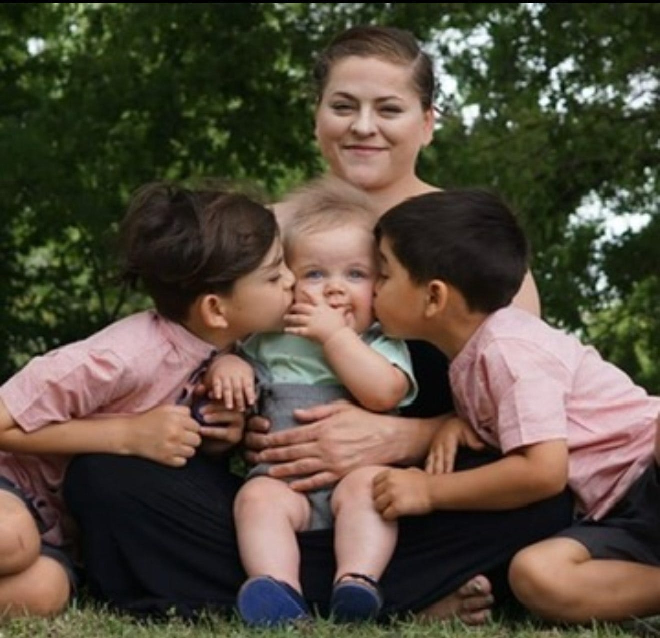 A mom sitting in a park with her three children