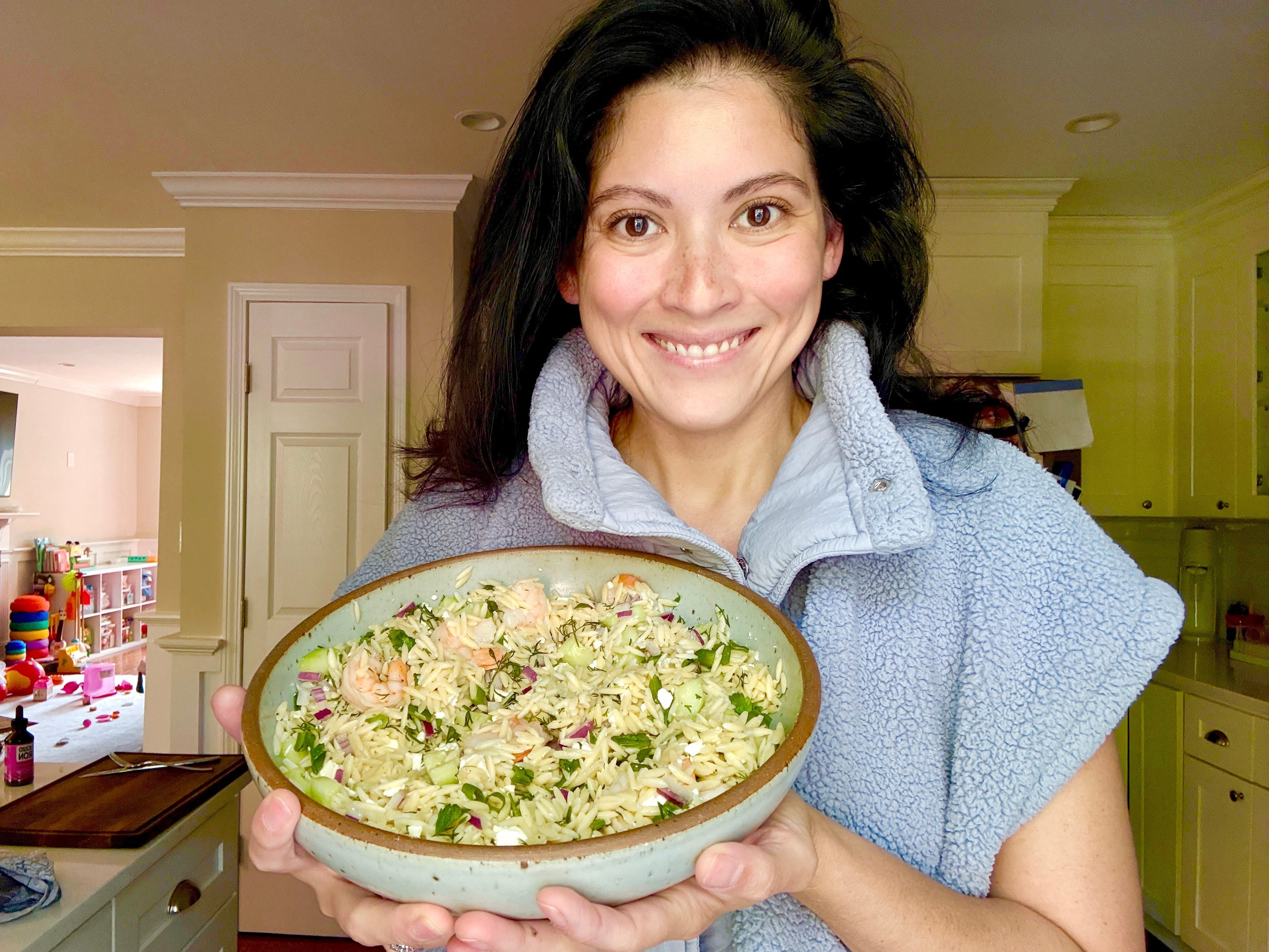 Lauren holding up a bowl of roasted shrimp and orzo.