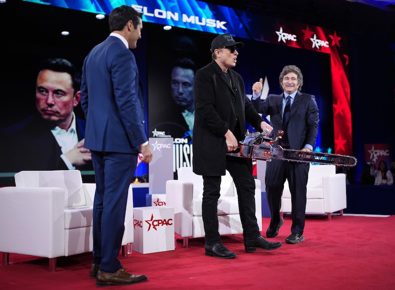 OXON HILL, MARYLAND - FEBRUARY 20: CEO of Tesla and SpaceX Elon Musk holds a chainsaw as he arrives on stage at the Conservative Political Action Conference (CPAC) at the Gaylord National Resort Hotel And Convention Center on February 20, 2025 in Oxon Hill, Maryland. The annual four-day gathering brings together conservative U.S. lawmakers, international leaders, media personalities and businessmen to discuss and champion conservative ideas. Musk was joined on stage by Argentine President Javier Milei, who gifted Musk the chainsaw he used as a prop while campaigning. (Photo by Andrew Harnik/Getty Images)