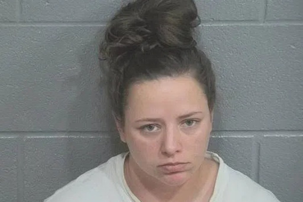 Mugshot of Krystal Sims with hair in a bun, wearing a light-colored shirt.