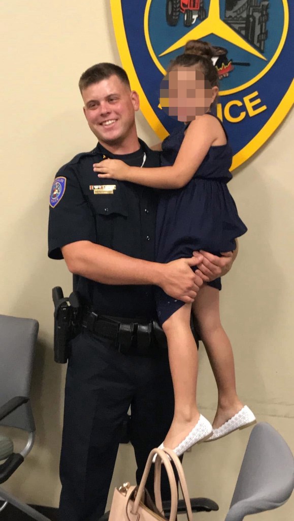 A male police officer in uniform holding a young girl.