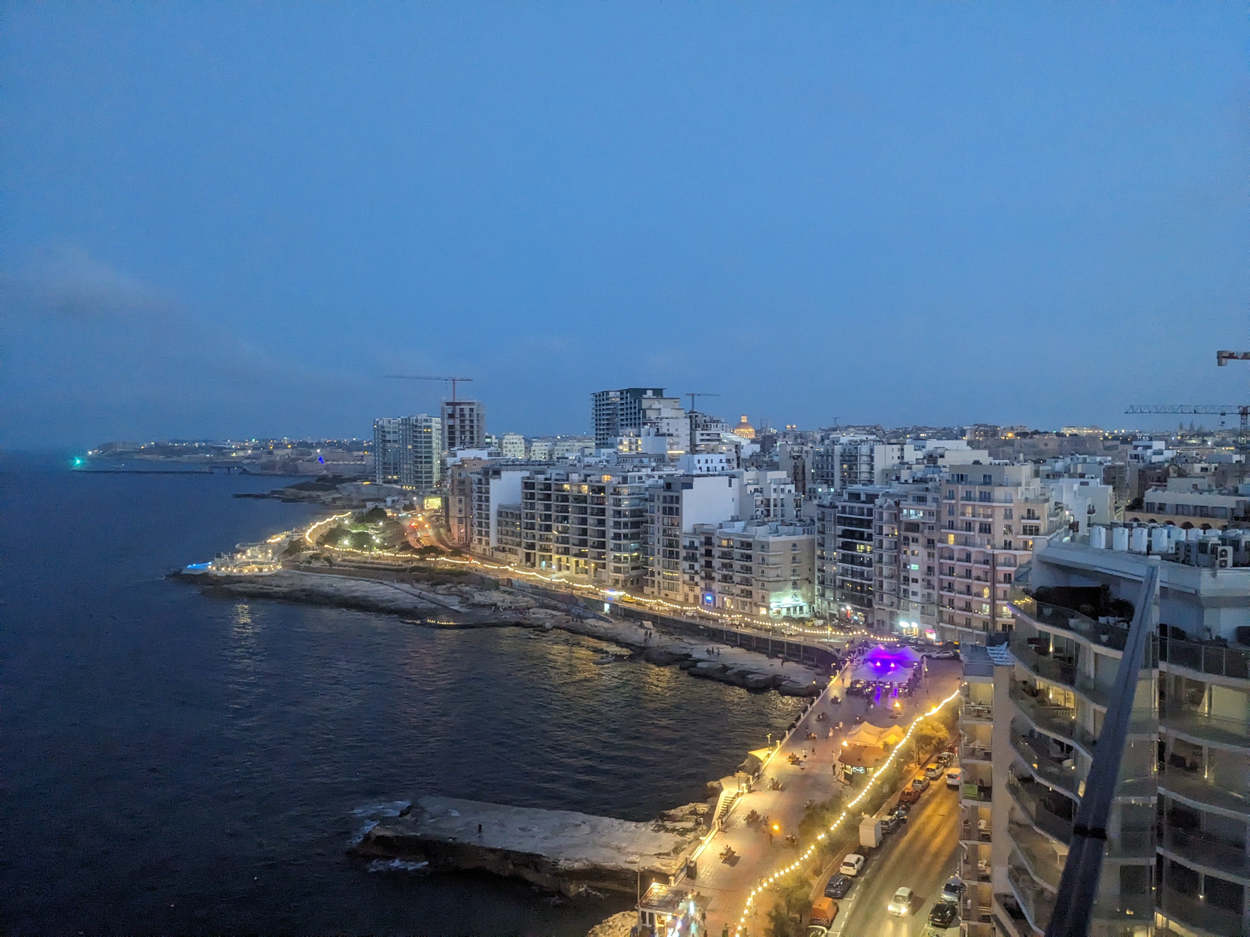 Aerial view of Malta coastline at night, with lit-up hotels and buildings
