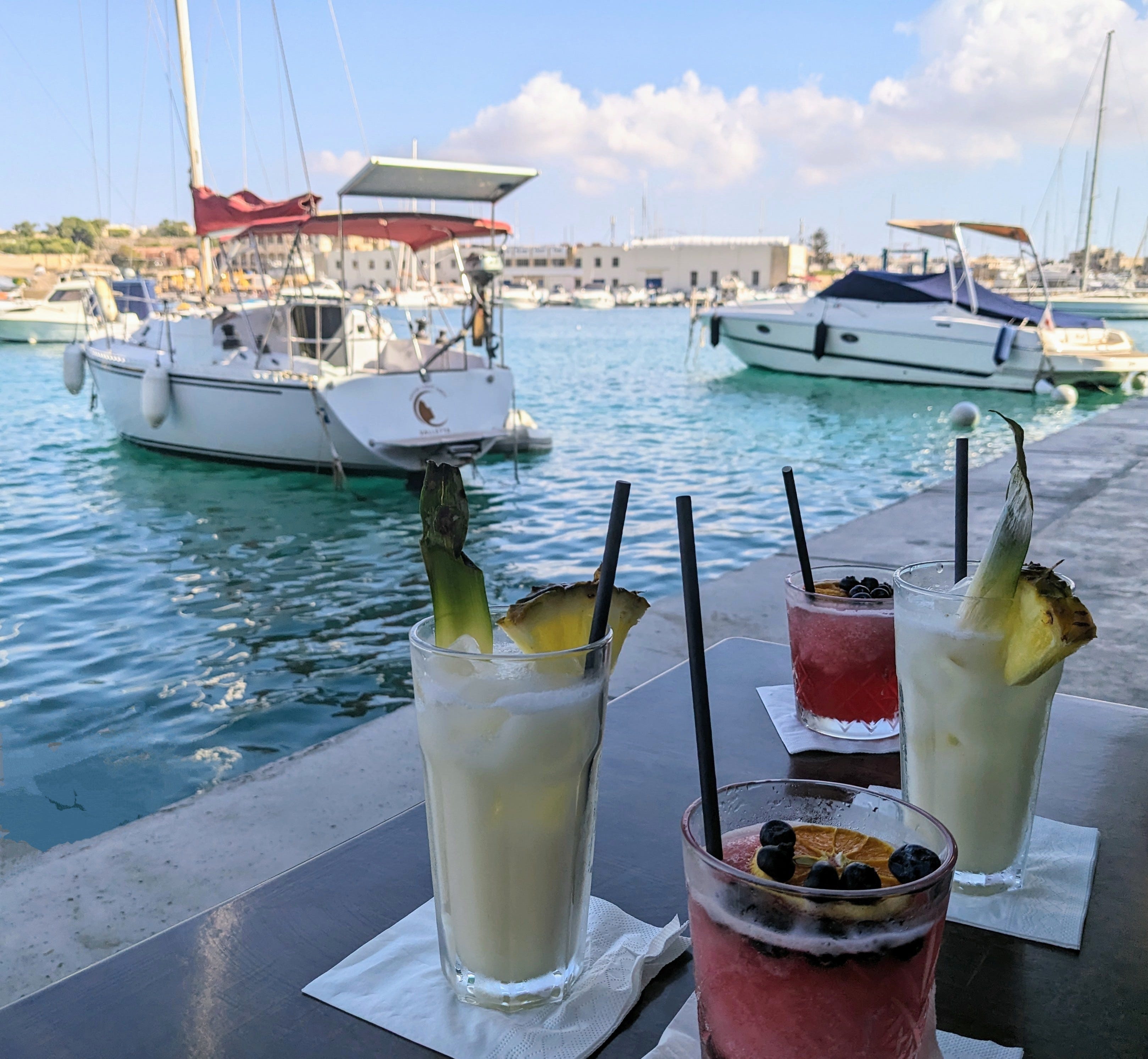 Cocktails on napkins next to boats on blue waters