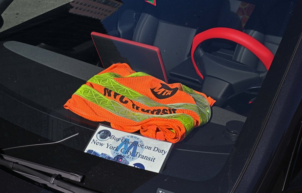New York City Transit Bus Operator on Duty placard and an orange safety vest on a car dashboard.