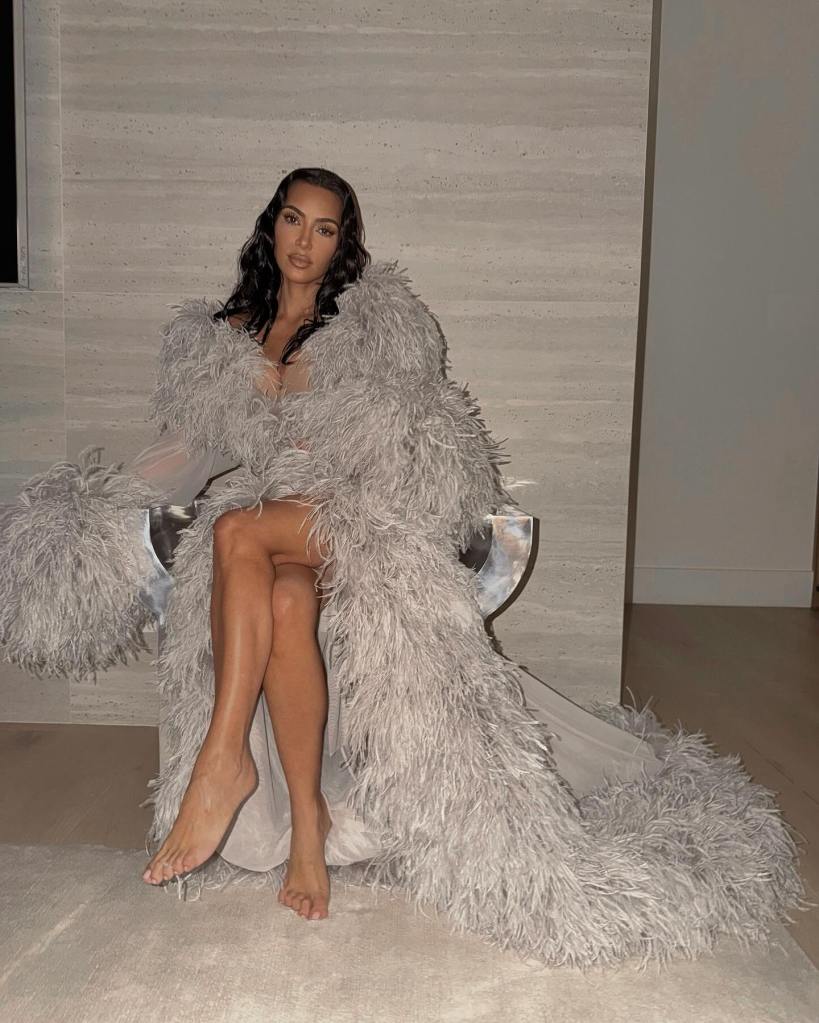 Kim Kardashian seated wearing a long, feathered robe.