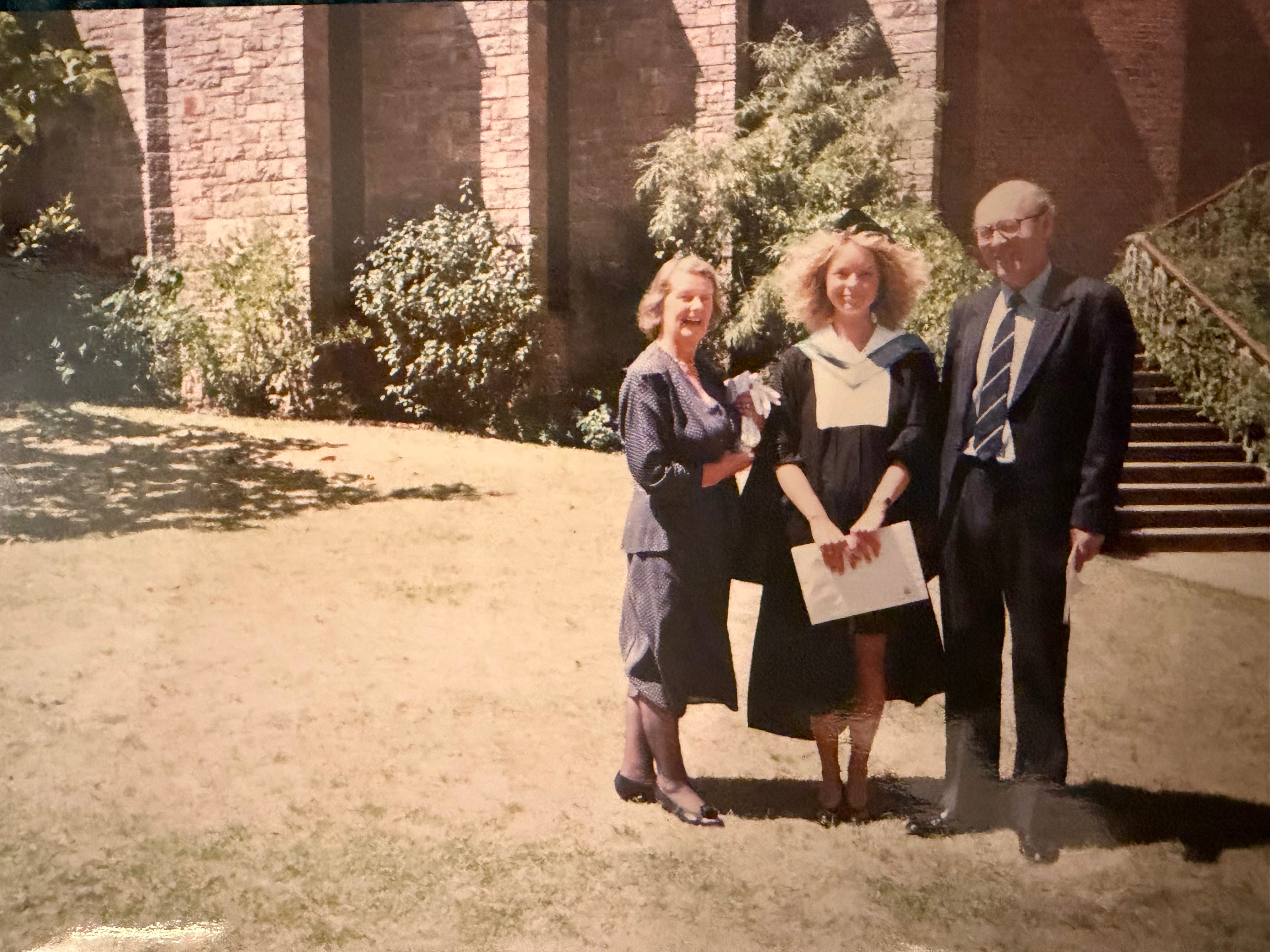 A new graduate with her parents standing on either side of her.