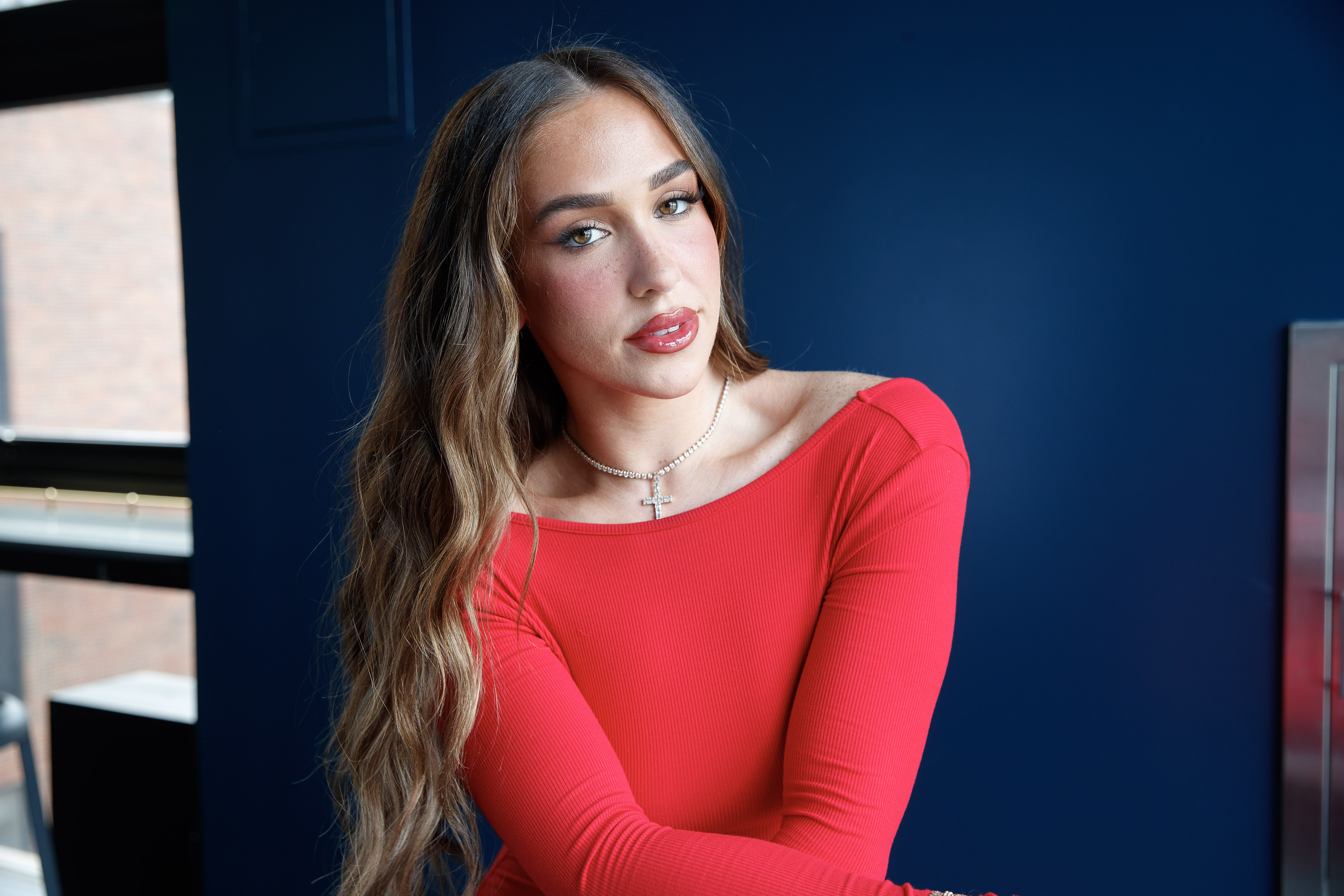 Ariana Biermann in a red top with a cross necklace.