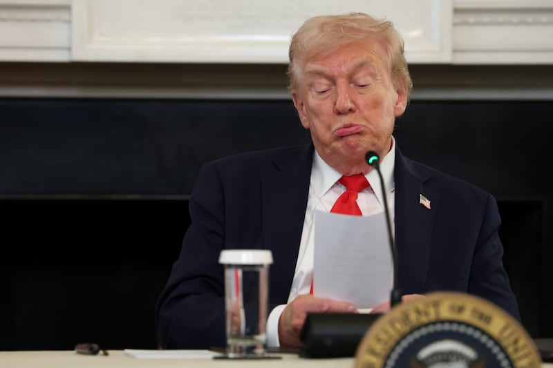 President Donald Trump reads a note handed to him by Secretary of State Marco Rubio during a roundtable discussion in the State Dining Room of the White House on October 8, 2025 in Washington, D.C.