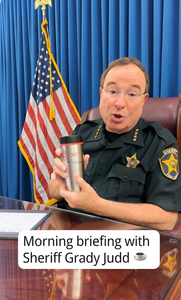 Sheriff Grady Judd in uniform holding a thermos during a morning briefing.