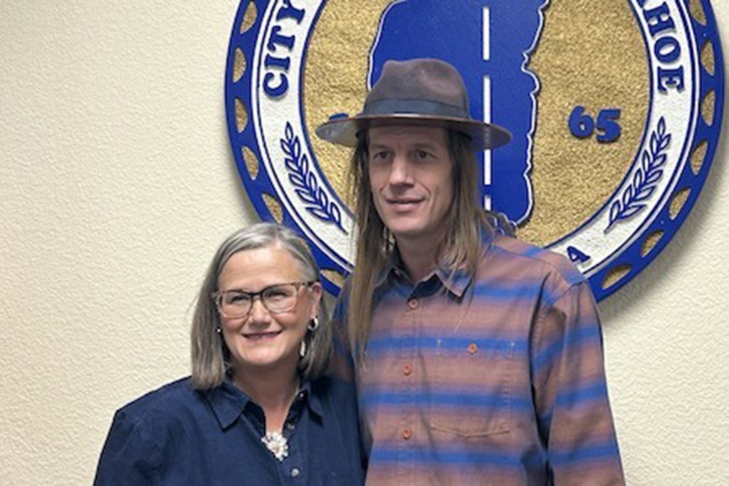 South Lake Tahoe Mayor Tamara Wallace with a man standing in front of the city's emblem.