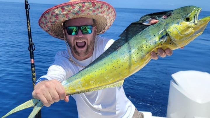 Dave Linder holding a mahi-mahi fish on a boat.