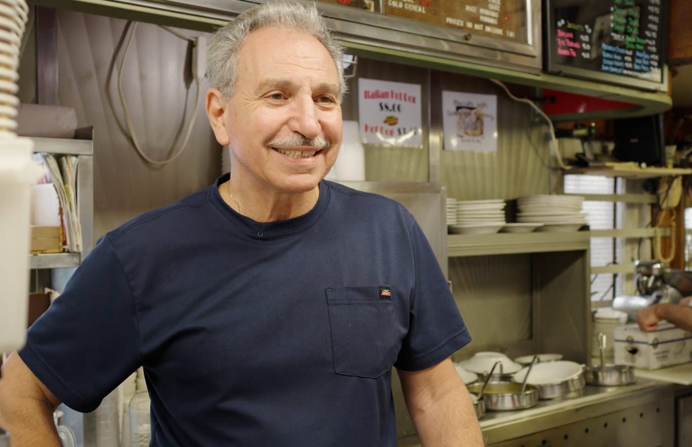 man in blue t-shirt standing inside of Summit Diner behind counter