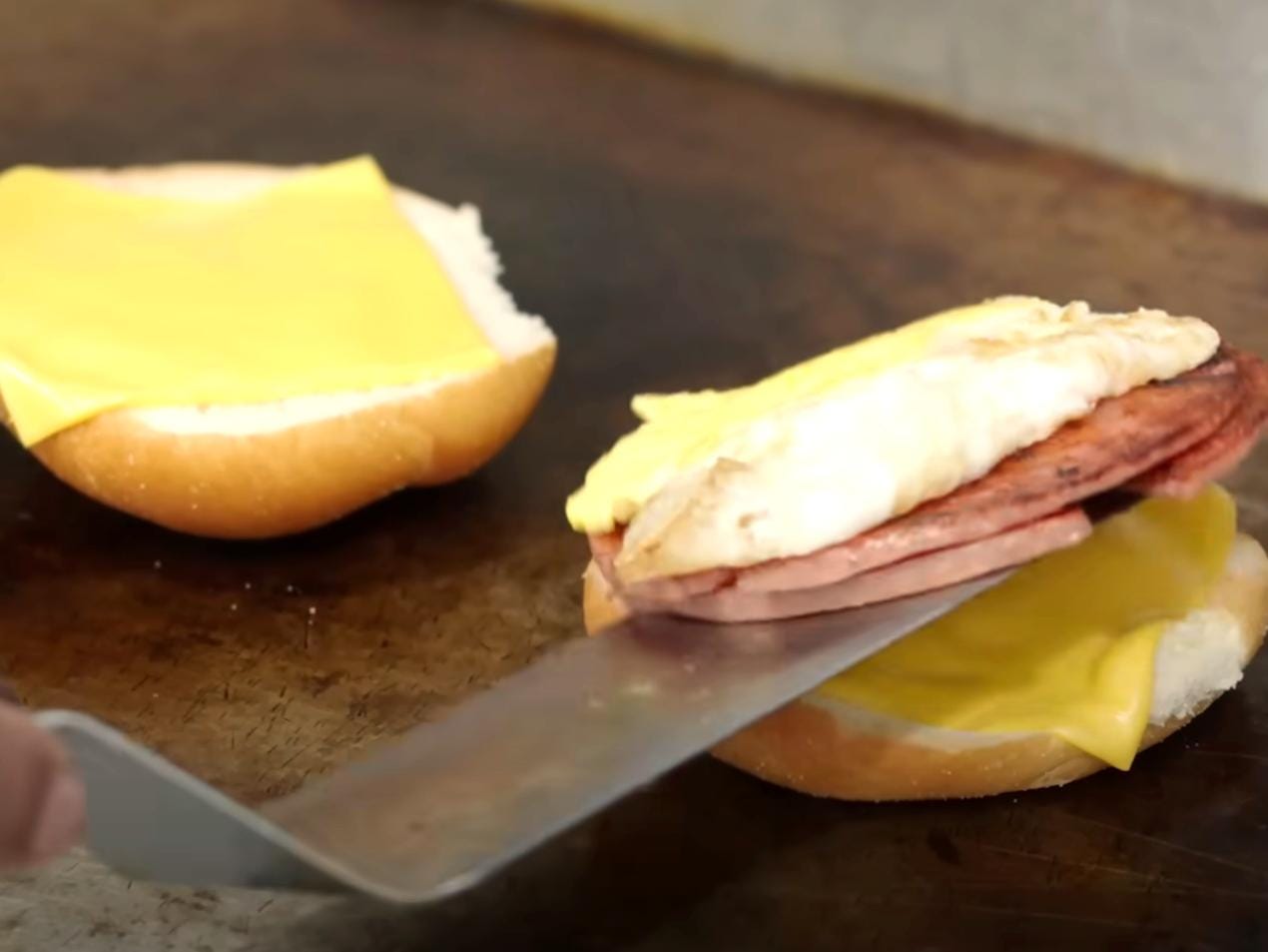 A white rolle with chese, egg, and ham on it.