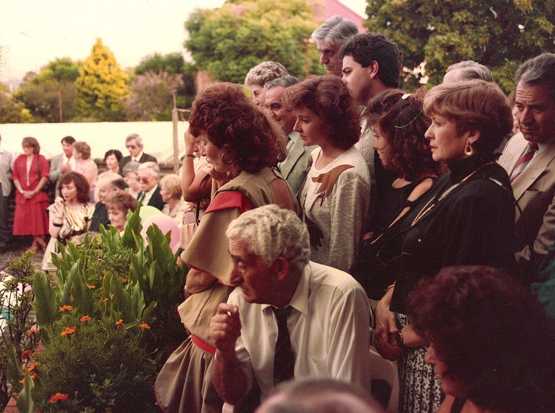 Group of people in workwear crowded in backyard in vintage photo