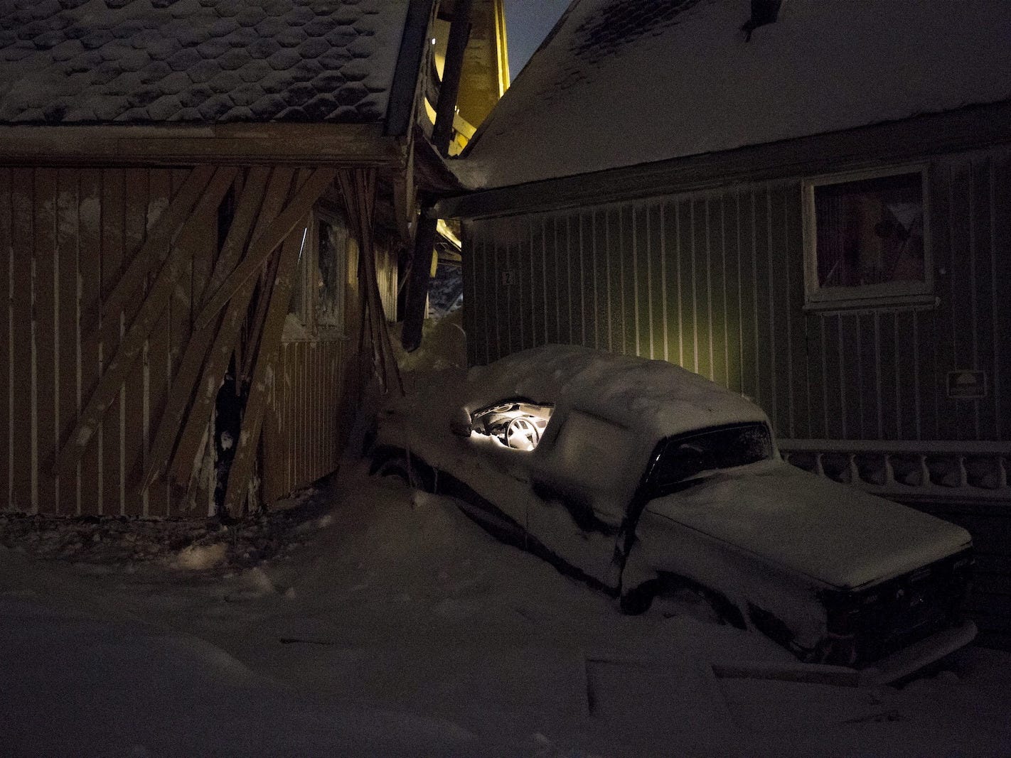 Lights are left on inside a car which was jammed between two houses pushed together by the force of Saturday's avalanche which hit the Norwegian town of Longyearbyen, the biggest settlement on the Arctic archipelago of Svalbard, roughly midway between the North Pole and the northernmost tip of Europe, December 20, 2015.