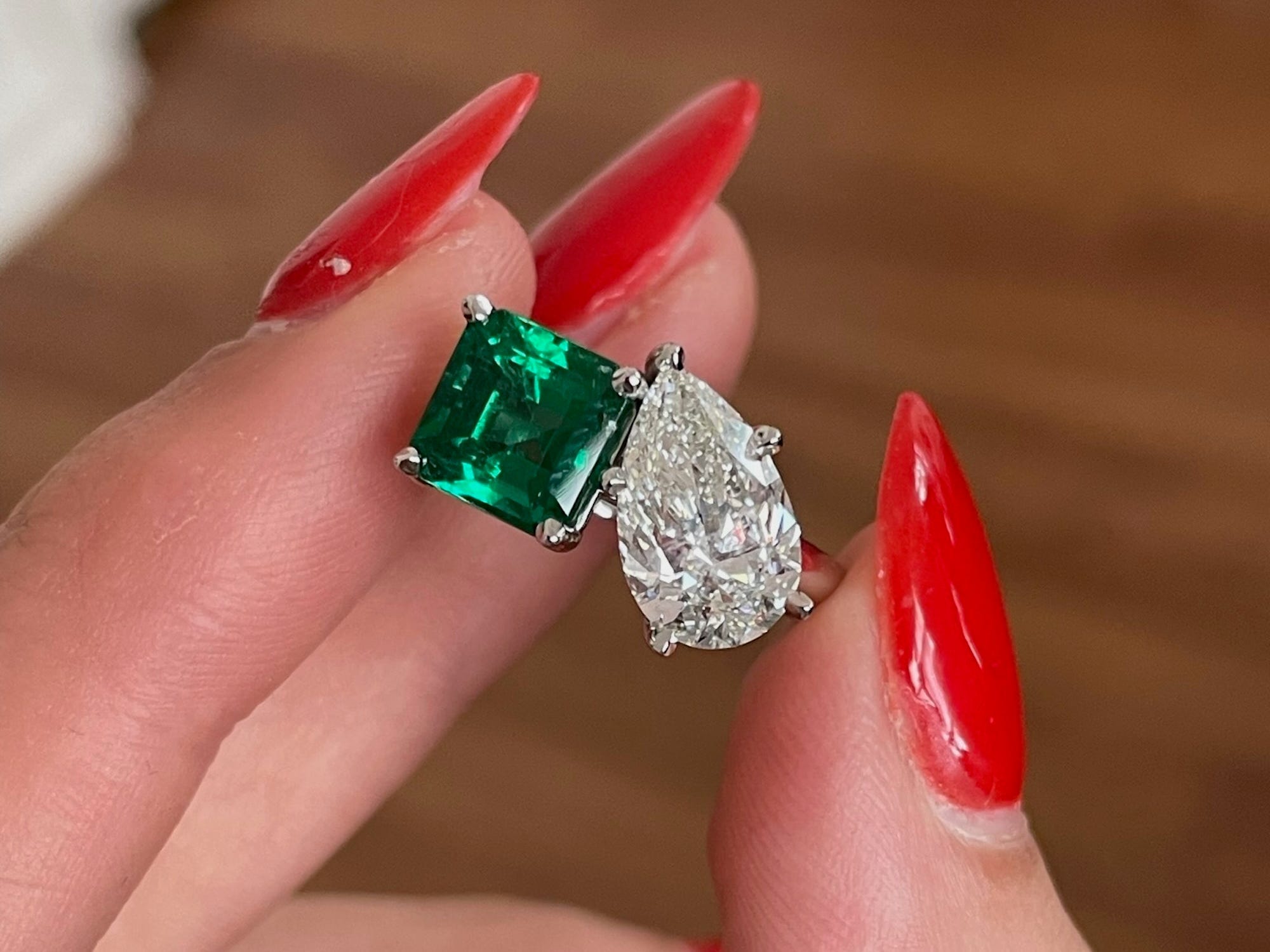 A toi-et-moi engagement ring with an emerald and an oval diamond.