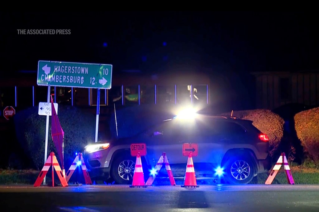 A police vehicle with flashing lights at a crime scene at night.