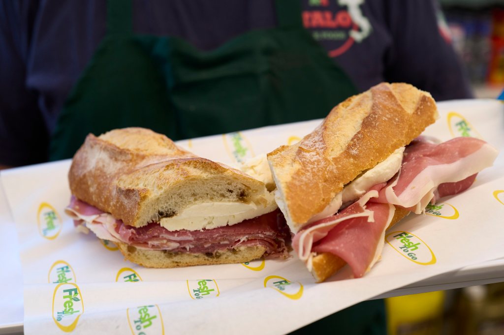 Italo Perito holding a fresh mozzarella and prosciutto sandwich.