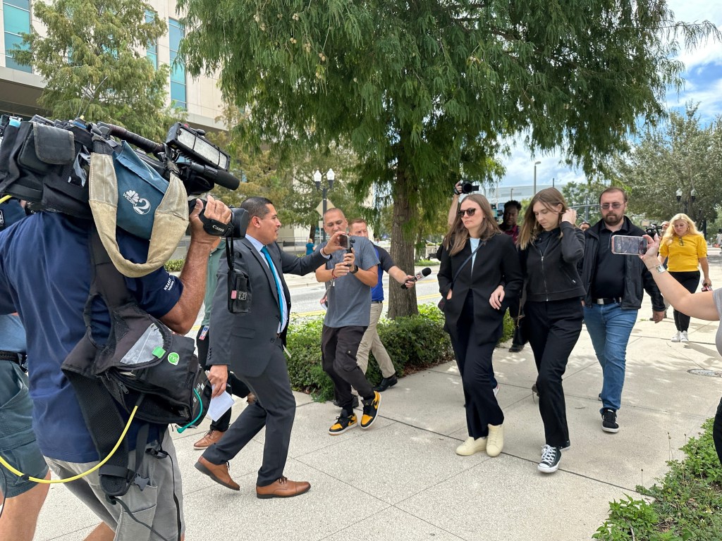 Siblings of a California wildfires suspect walk outside a federal courthouse, surrounded by media.