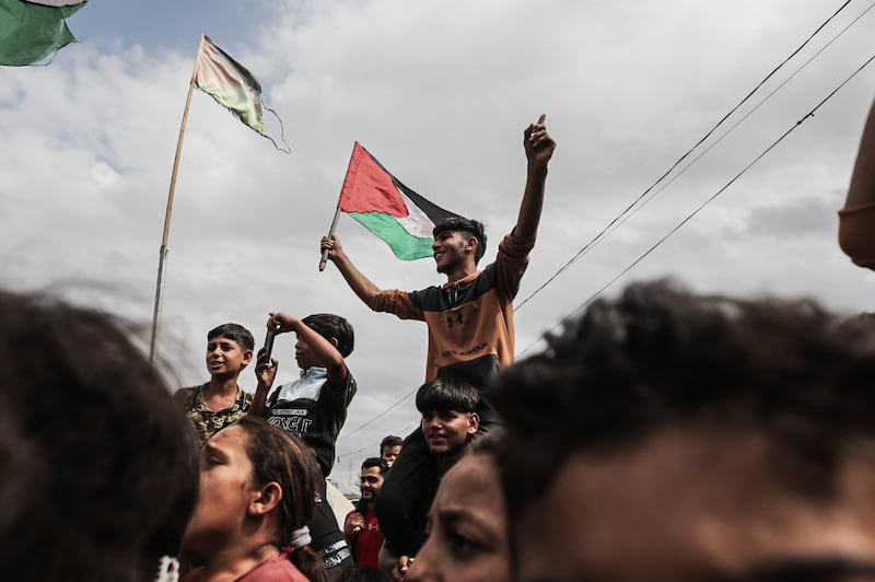 Palestinians gathered at the Nuseirat refugee camp celebrate with Palestinian flags after the announcement of a ceasefire agreement on October 9, 2025 in Deir al-Balah, Gaza.