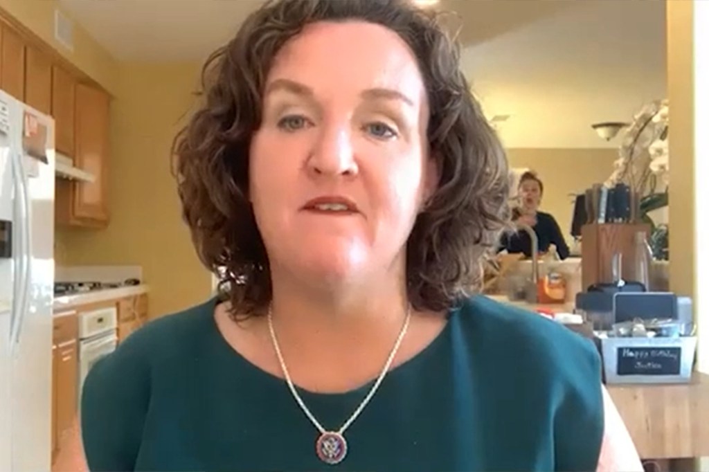 Katie Porter in a video call with a staffer visible in the background reflection.