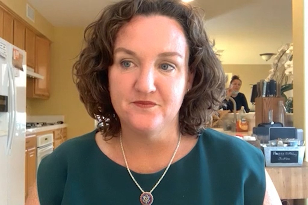 Katie Porter speaking on camera, with a staffer in the background wearing a mask.
