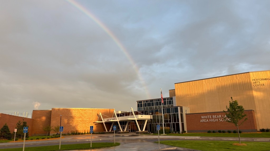 White Bear Lake Area High School with a rainbow arching over the building.