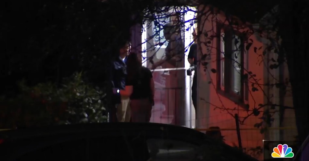 Police investigation scene at night with a red light on the building and caution tape.